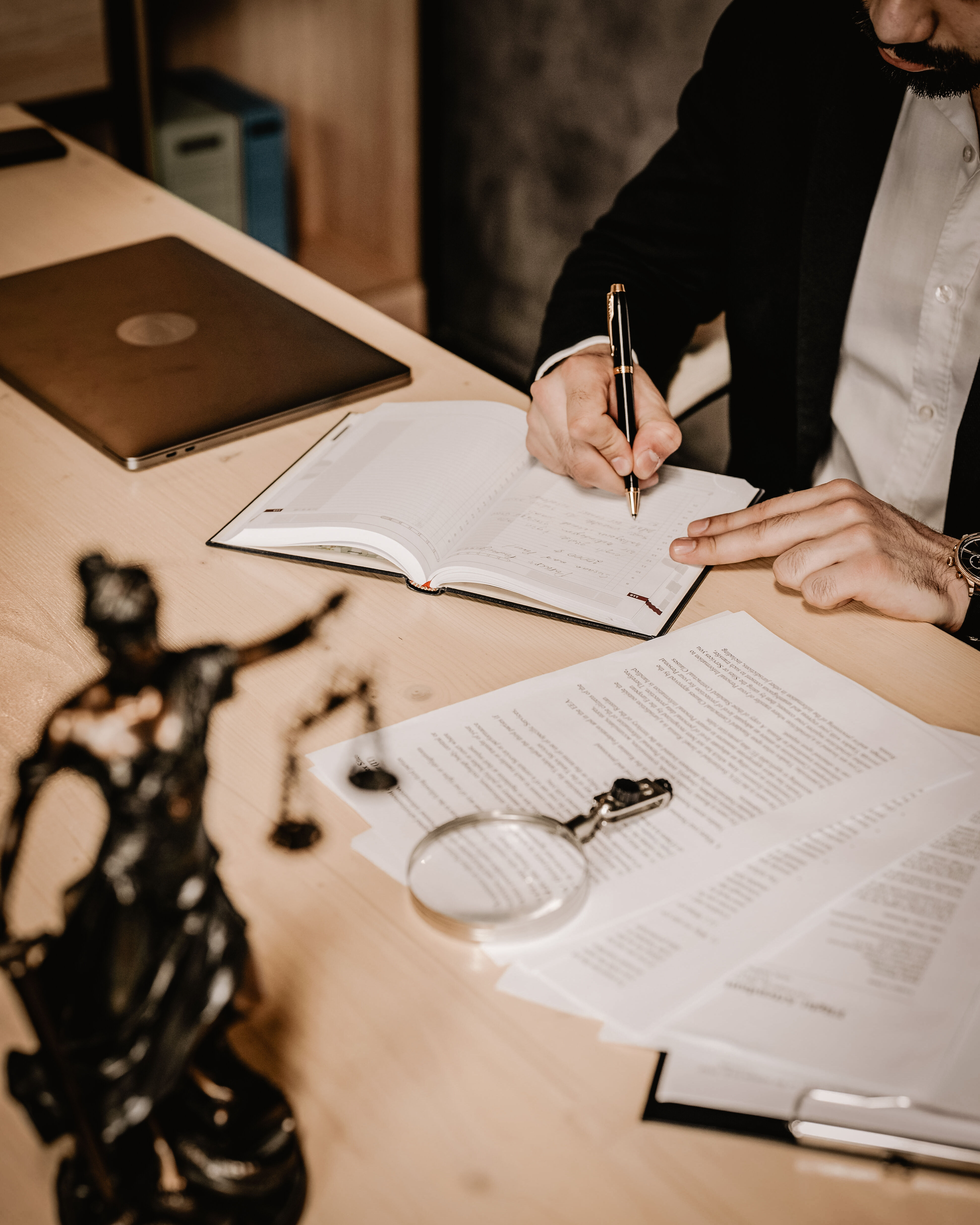 Lawyer in an office writing in a book with legal documents on the desk